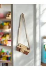 Kahverengi ahşap fotoğraf makinesi oyuncak, doğal malzemelerle üretilmiştir ve çocuk odalarına zarif bir aksesuar olarak eklenebilir. Eğitici ve eğlenceli özellikleriyle çocukların gelişimine katkı sağlar.