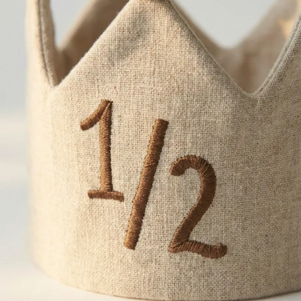 Sık iğne nakış işlemeli 1/2 yazılı bebek tacı ve pamuklu kumaş dokusu